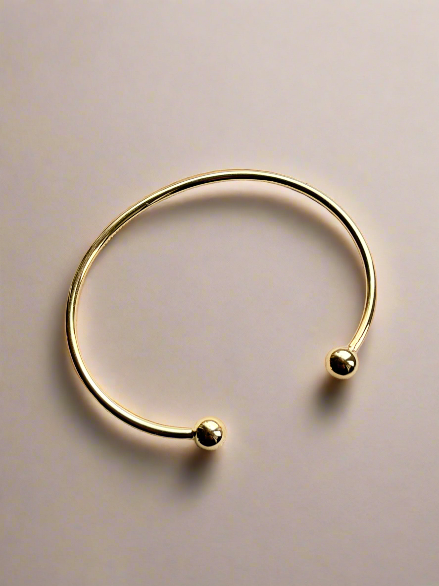Gold cuff bracelet  ends on a beige background