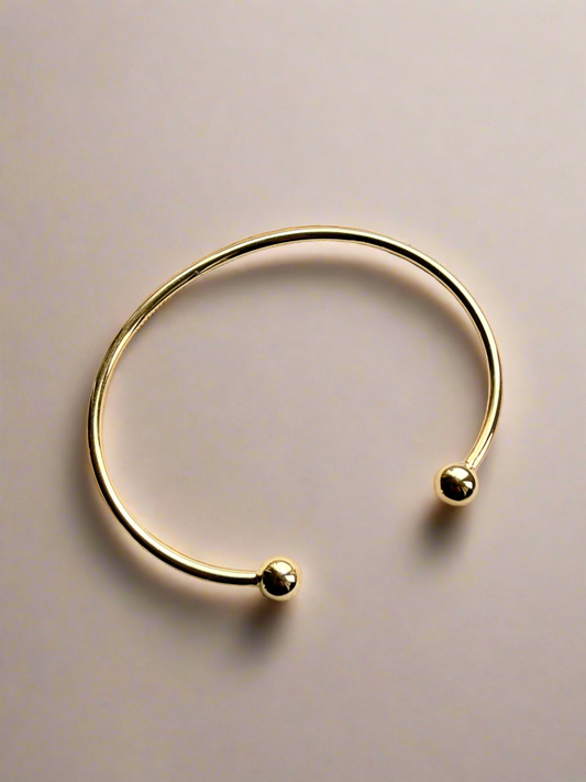 Gold cuff bracelet  ends on a beige background