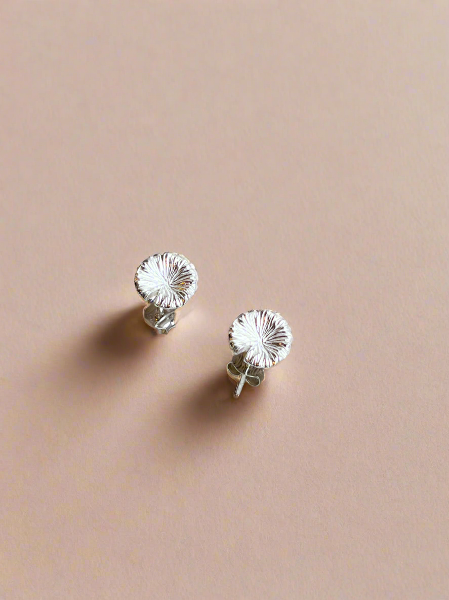 Silver floral stud earrings on a beige background