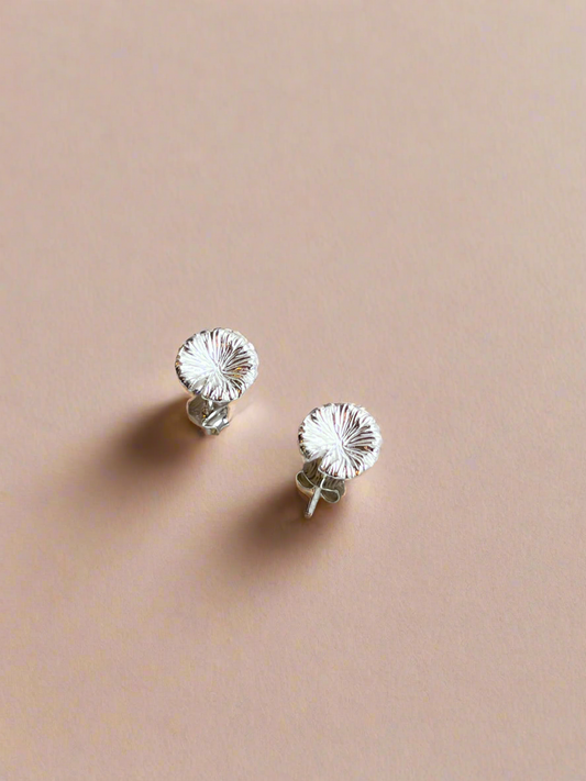 Silver floral stud earrings on a beige background