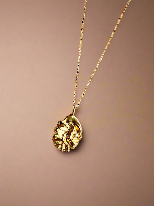Gold necklace with a pendant on a brown background