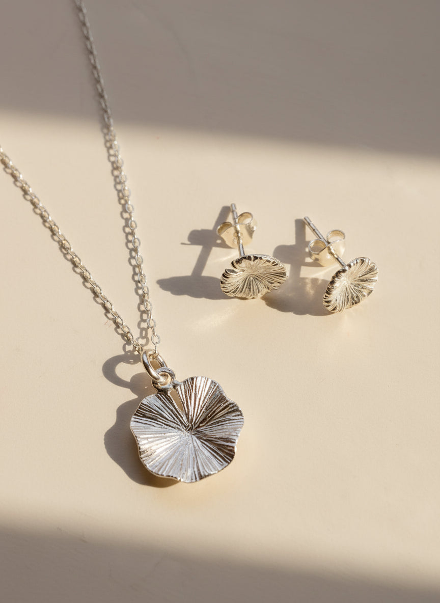 Silver necklace and earrings on a light gray surface