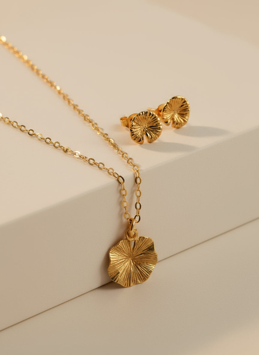 Gold necklace and earrings on a textured white surface