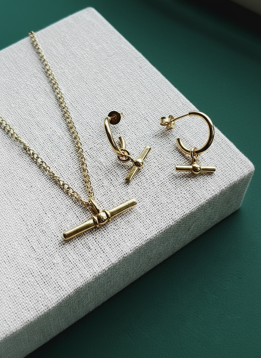 Gold necklace and earrings on a textured white surface