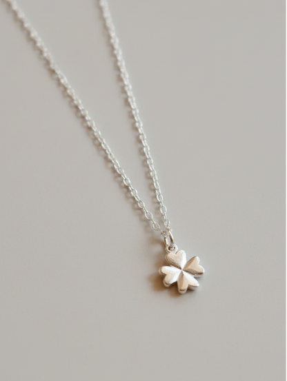 Silver necklace with a four-leaf clover pendant on a light gray background